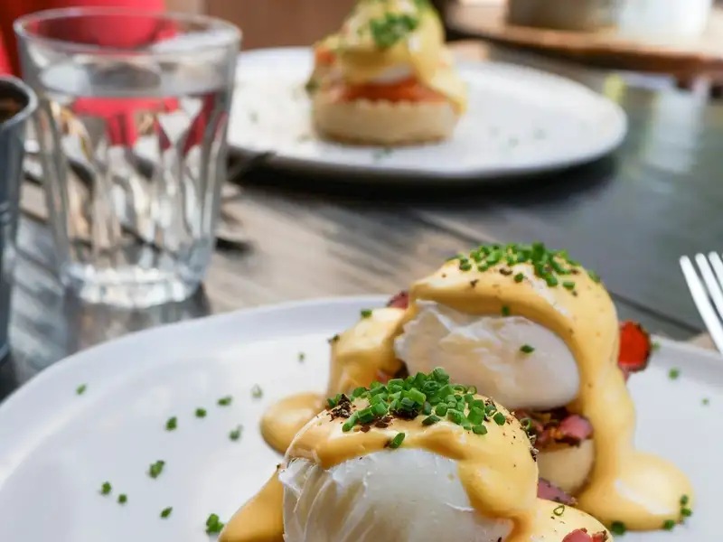An eggs Benedict in daylight: poached egg, hollandaise and chives over peameal bacon on an English muffin