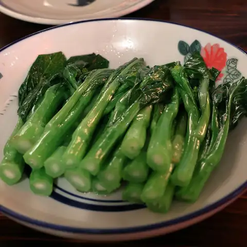 Glossy stems of Chinese broccoli on a blue-rimmed plate