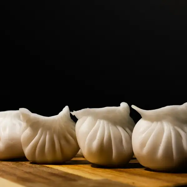 A row of pleated shrimp dumplings on a wooden board