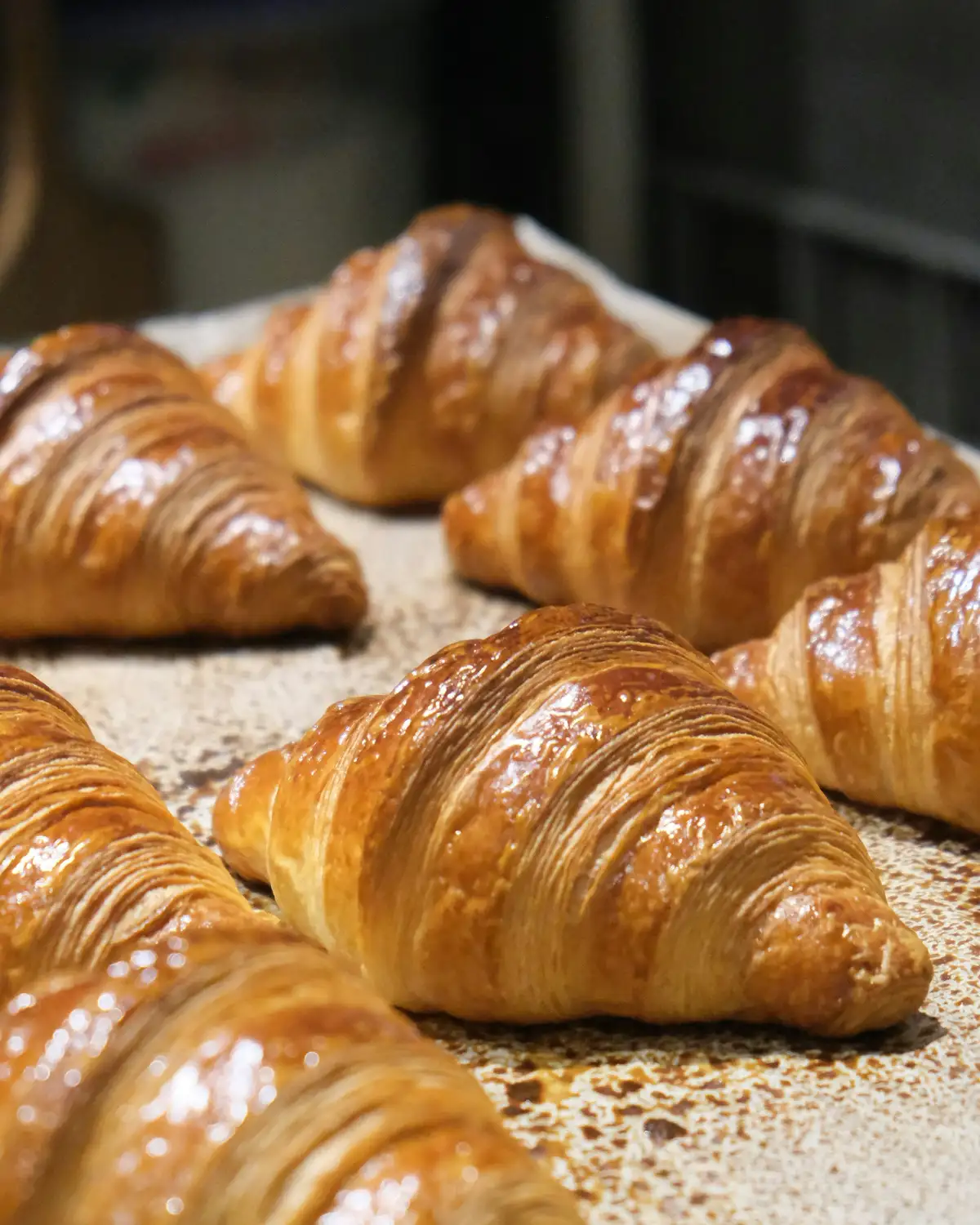 Golden croissants cooling on a baking tray dusted with flour