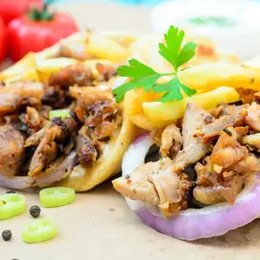 A shawarma wrap cut in half, packed with grilled chicken, fries and pickles