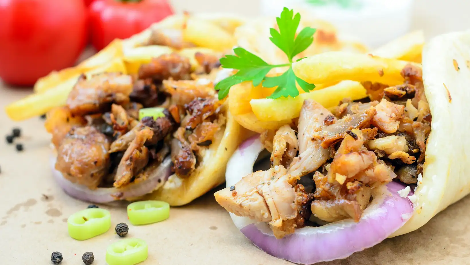 A shawarma wrap cut in half, packed with grilled chicken, fries and pickles