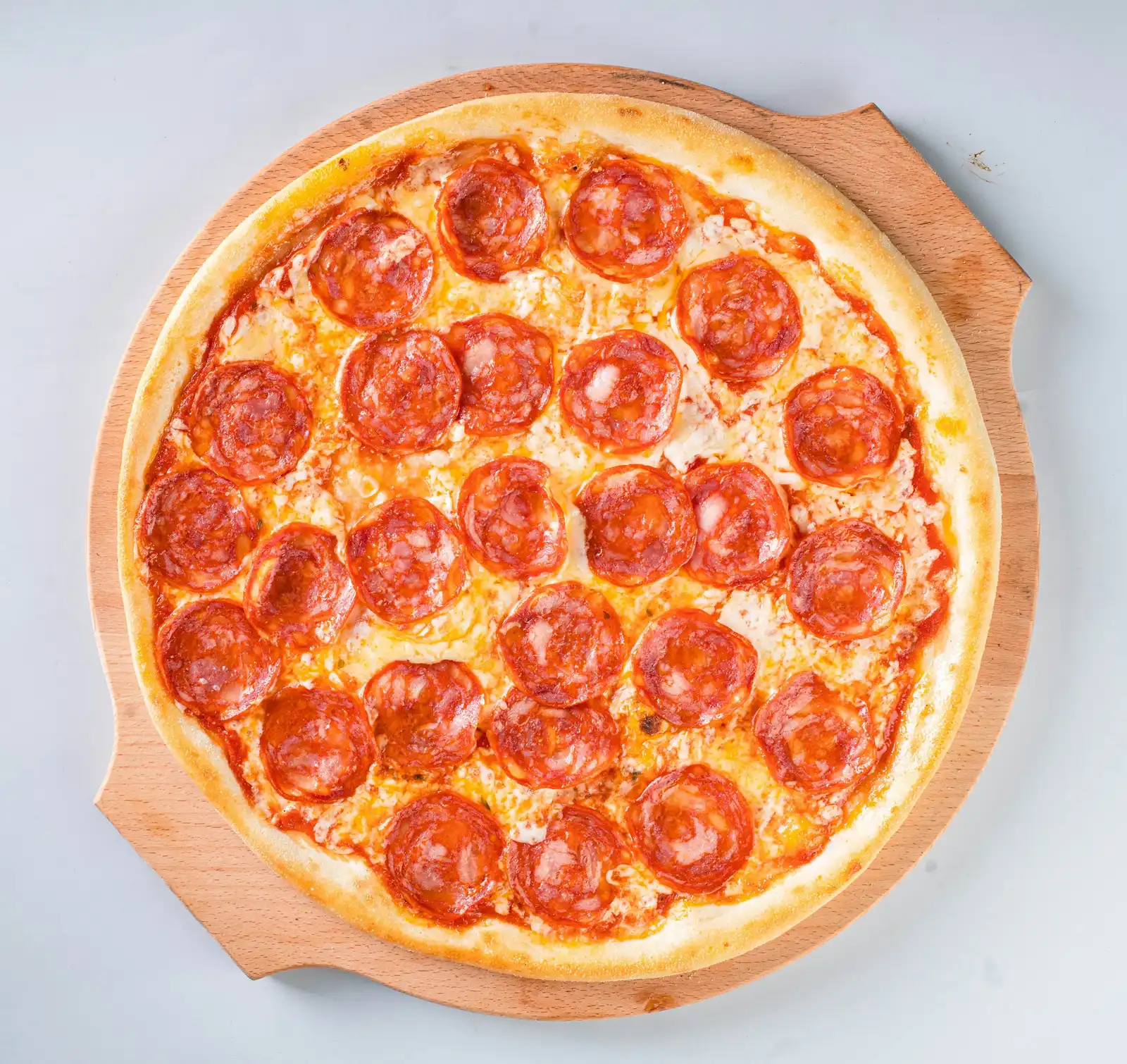 The Twofold, our house pie: a whole pepperoni pizza from above on a wooden peel