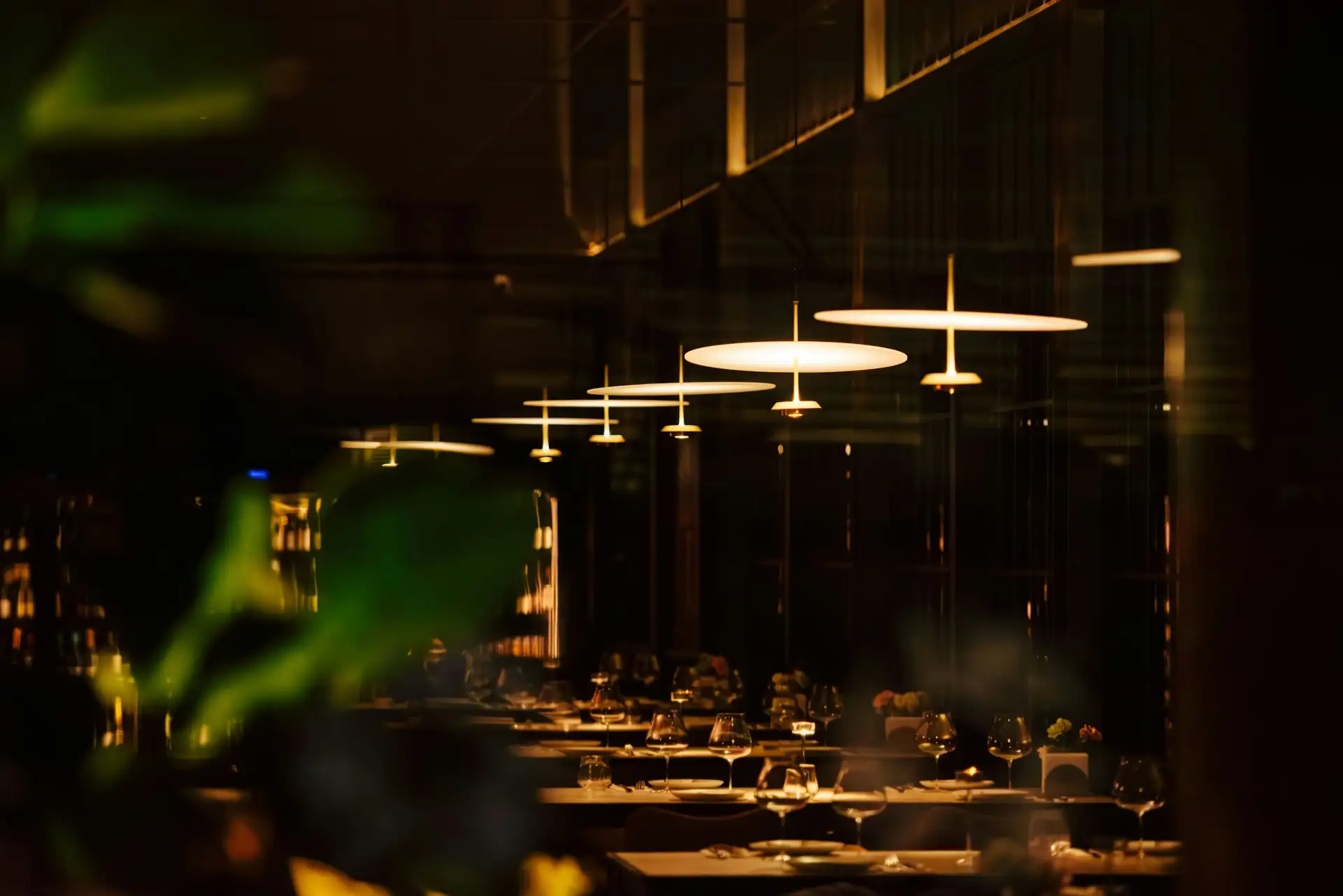 The dining room at night, pendant lamps hung low over the tables