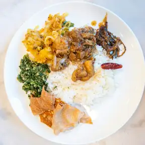 Shawarma over rice with greens and grilled vegetables on a white plate, from above