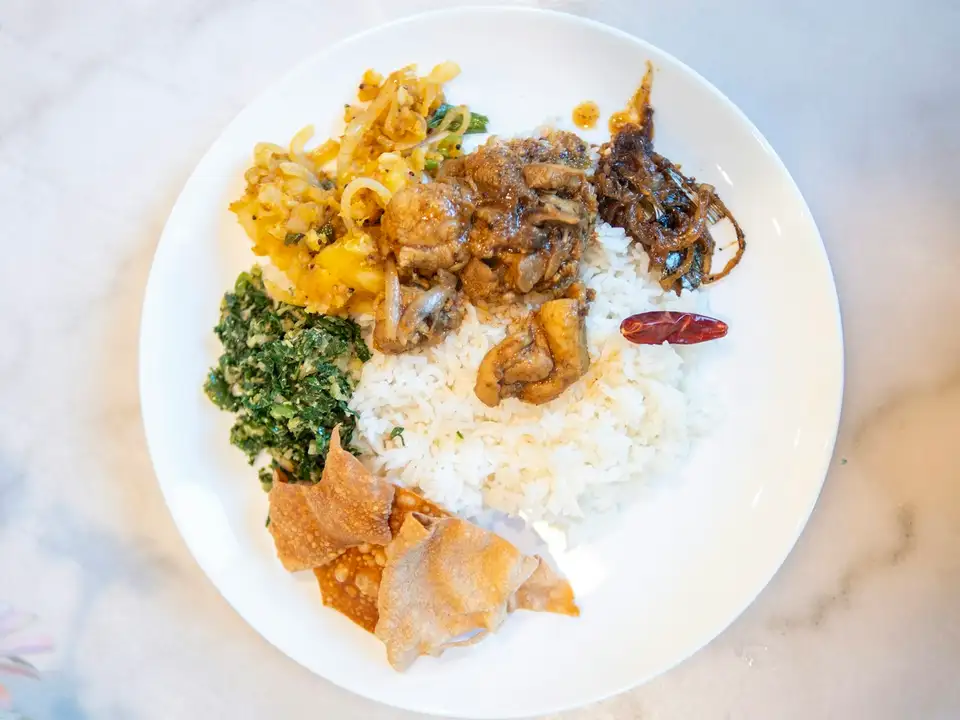 Shawarma over rice with greens and grilled vegetables on a white plate, from above