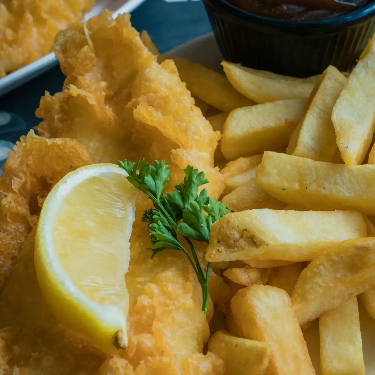Golden battered fish with thick-cut fries, a lemon wedge and tartar sauce