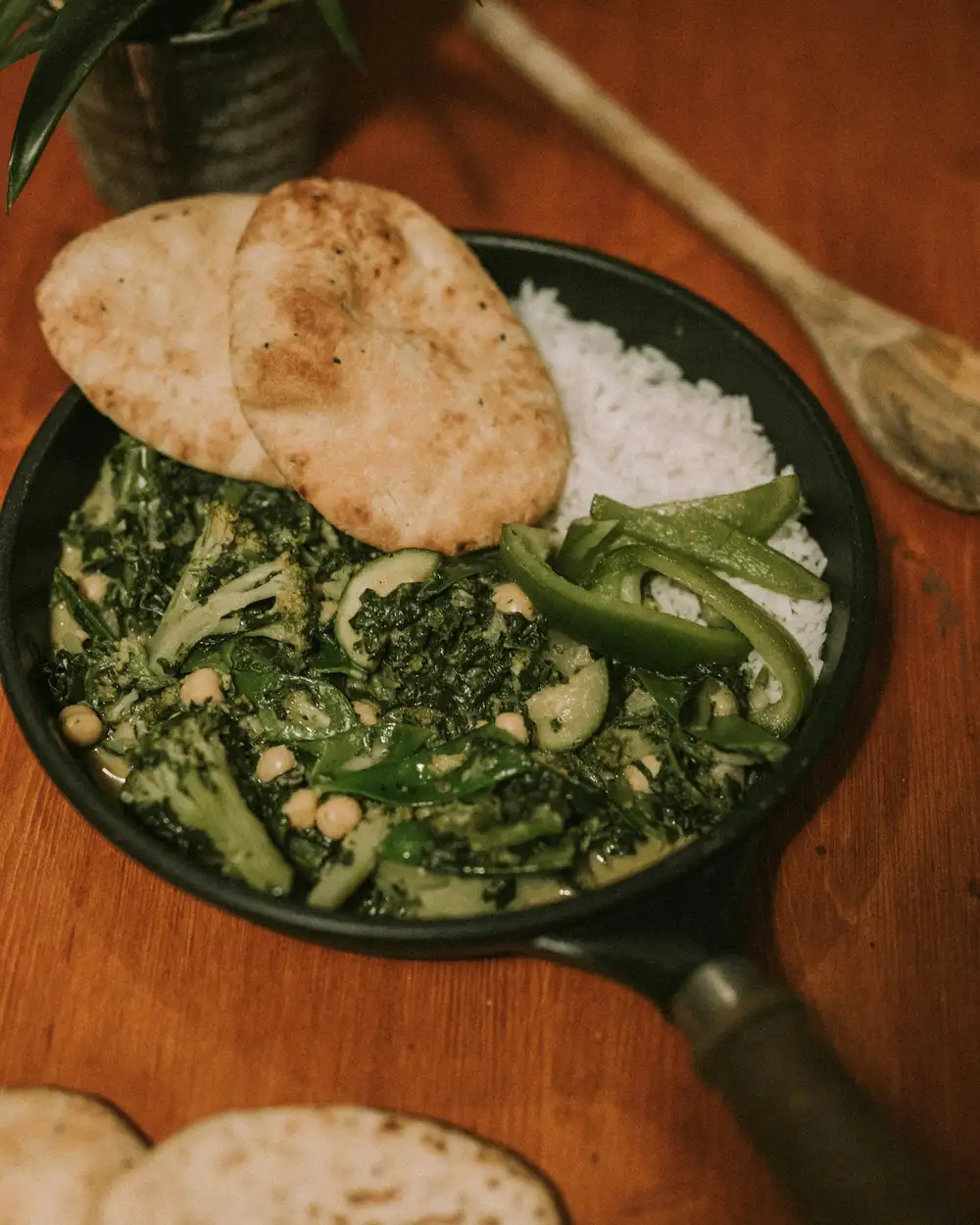 Saag with green chilies in a cast-iron pan, with roti and white rice on the side