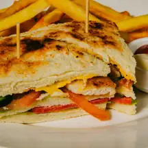 A toasted club sandwich held with toothpicks, a pile of fries and a cup of ketchup
