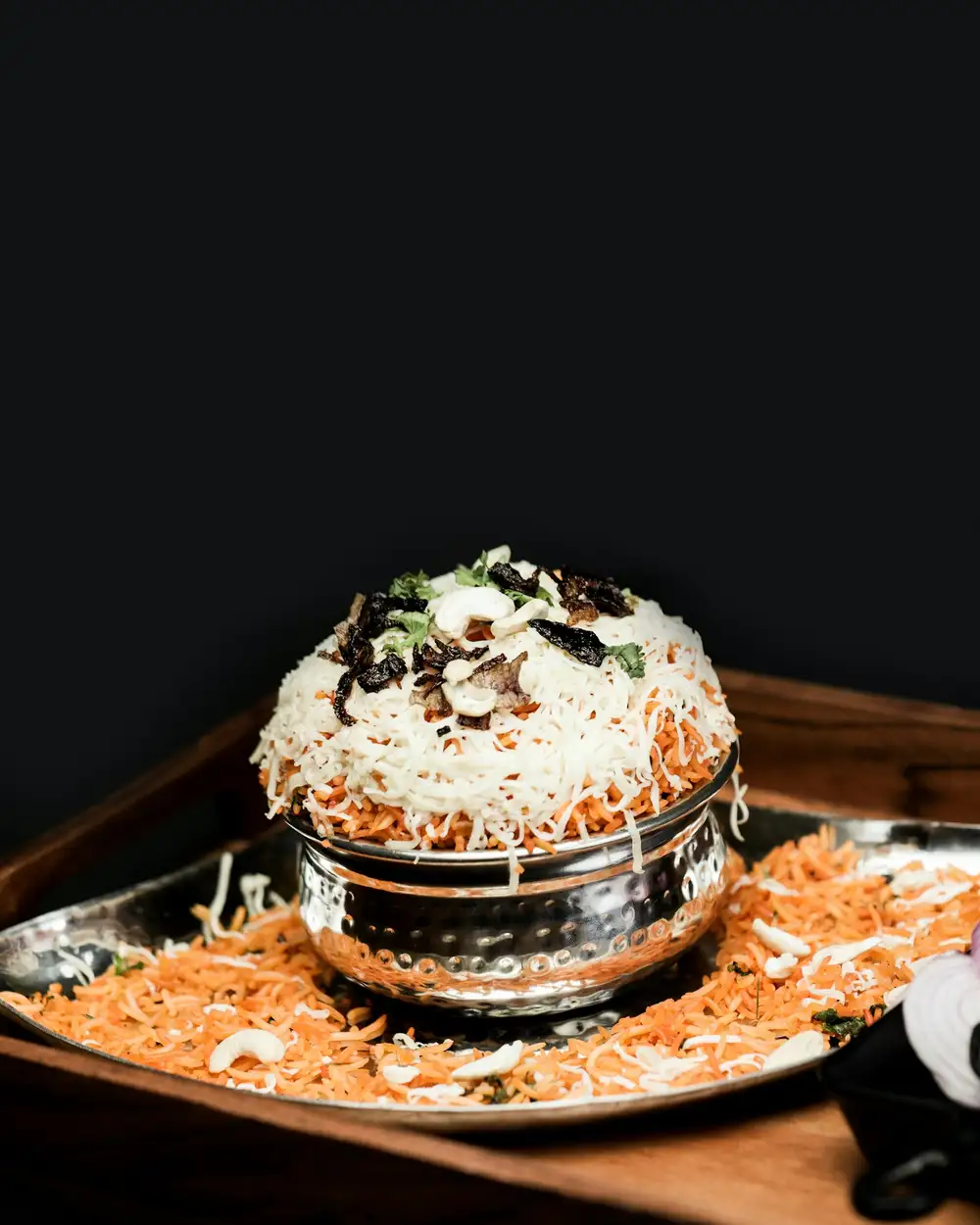 Chicken biryani in a steel handi with the lid off, topped with fried onions