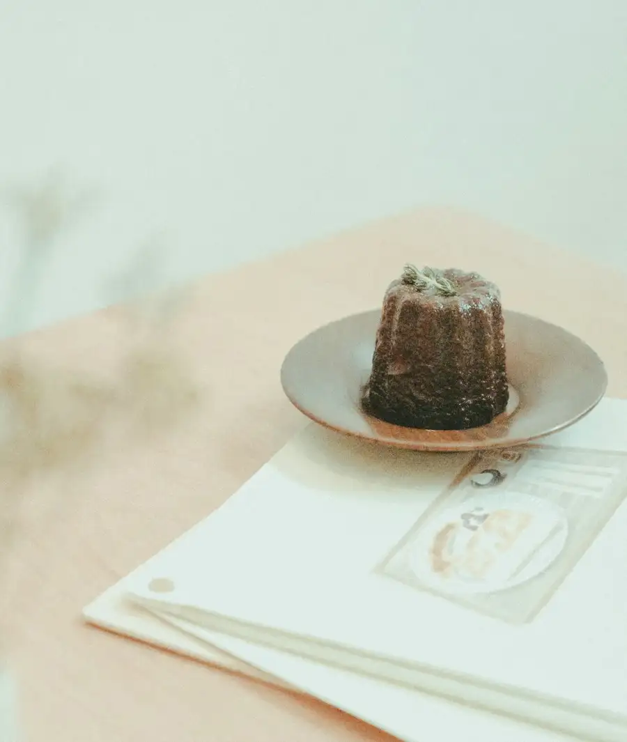 A dark, caramelised canelé on a small gold plate in soft morning light