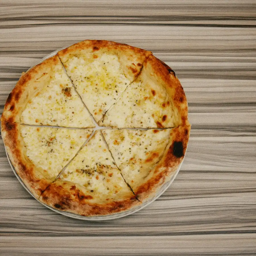 A white pizza, sliced, with golden melted cheese and a blistered crust