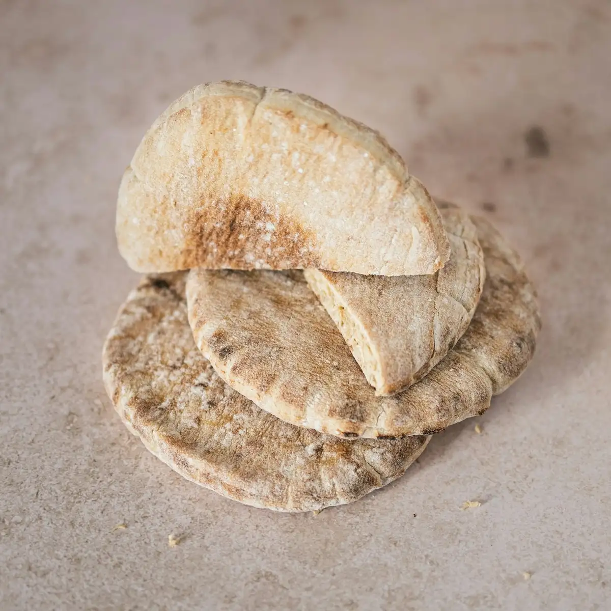 A warm stack of round pita breads on a stone counter