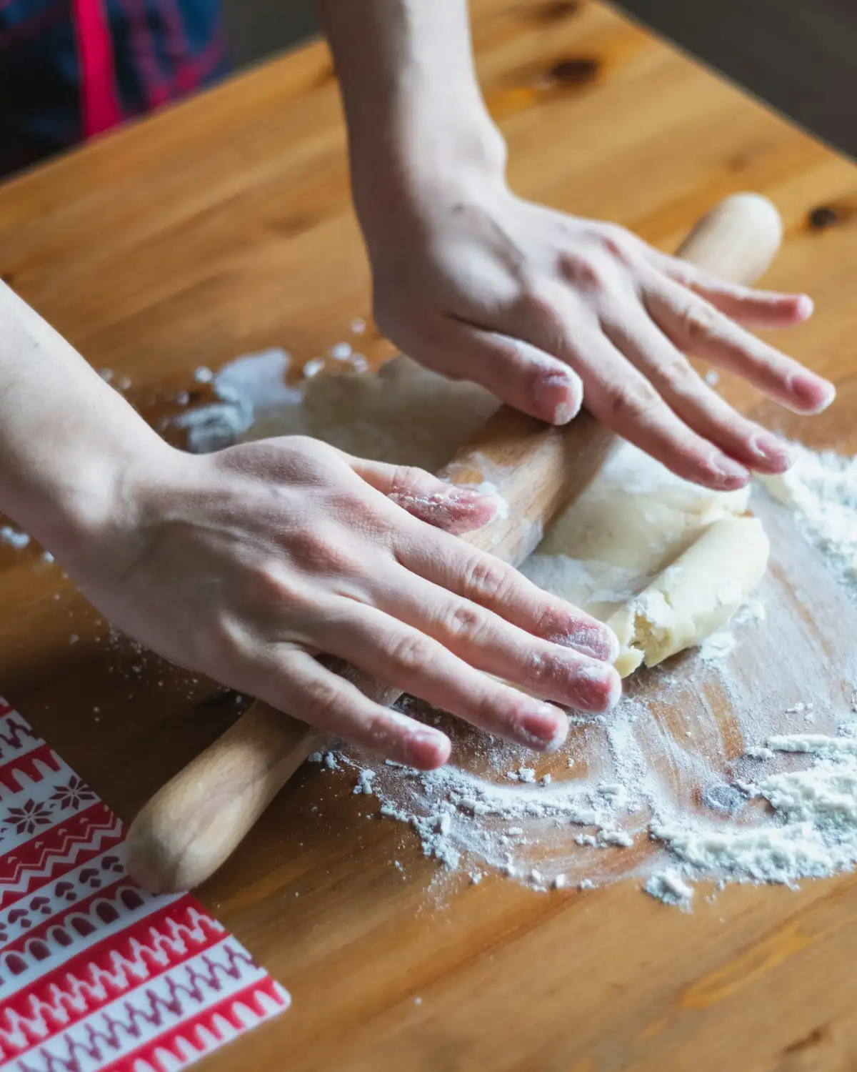 Hands rolling out laminated dough on a floured wooden table