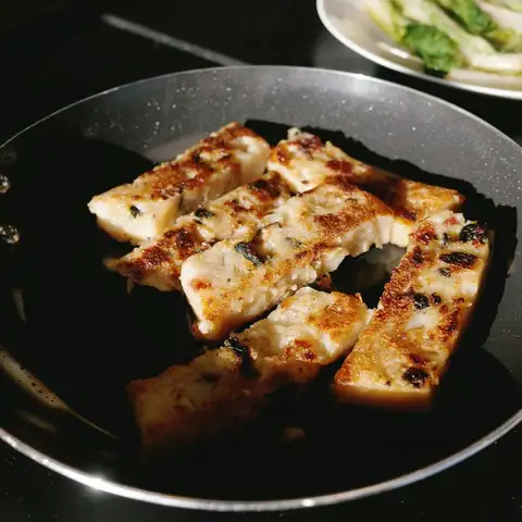 Squares of turnip cake seared golden in a pan